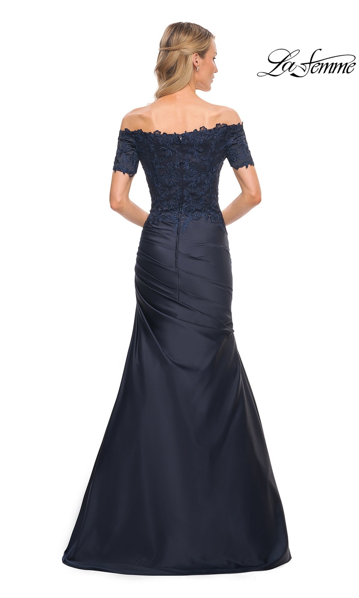 Back view of a woman wearing a La Femme 30199 dark navy, off-the-shoulder mermaid silhouette gown with short lace sleeves and a fitted, ruched skirt.